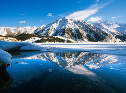 Big Almaty lake on december. Water, ice, mountains and snow.