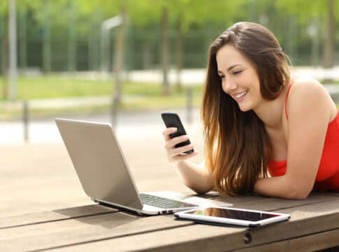 Girl using a laptop and smart phone in a park