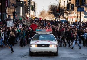 Police Car in front of the Protesters controlling the Traffic