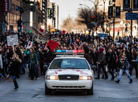 Police Car in front of the Protesters controlling the Traffic