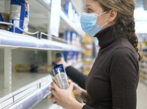 A woman in a medical mask takes the last bag of cereals in the store, empty supermarket shelves.